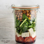 Meal Prep Salat im Glas mit Kichererbsen, Spinat, Feta und Tomaten – vegetarisches Mittagessen zum Mitnehmen